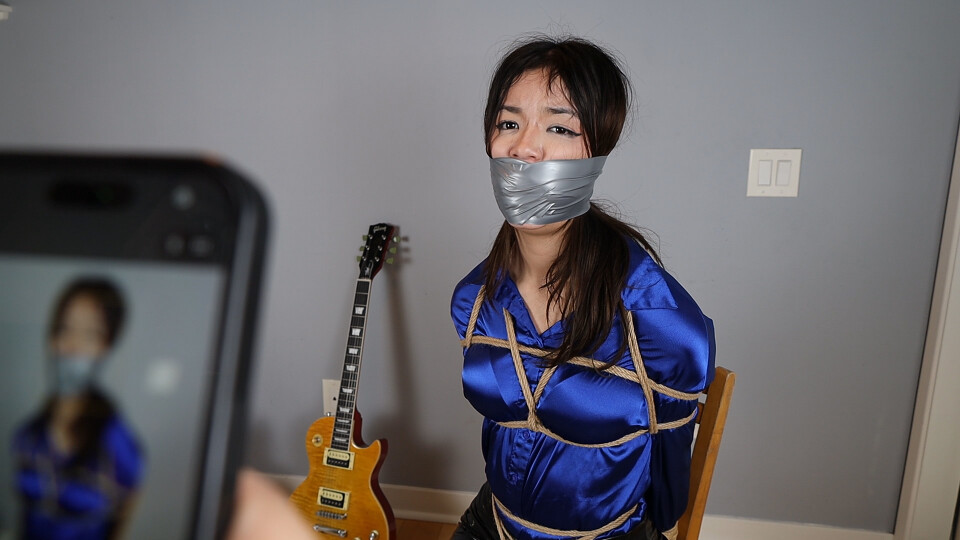 Kali Valentine in satin blouse and leather pants tightly tied up and extremely tightly wraparound tape gagged during the robbery of some top-secret documents